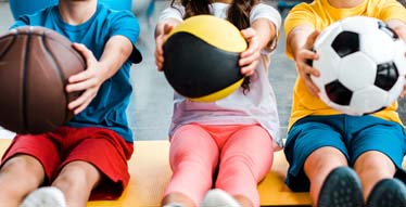 kids holding basketball and soccer ball
